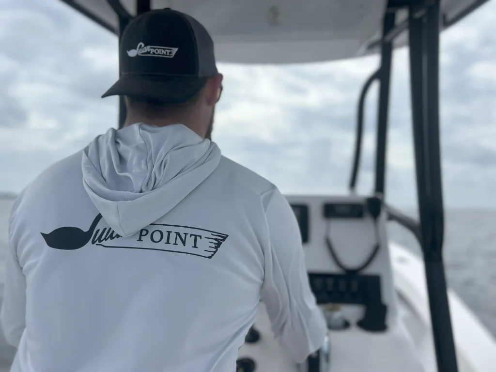 Person wearing a Swan Point hoodie while operating a boat
